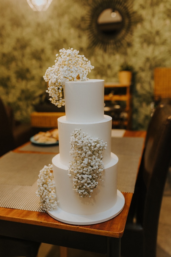 Beautiful elegant white wedding cake on table in restaurant