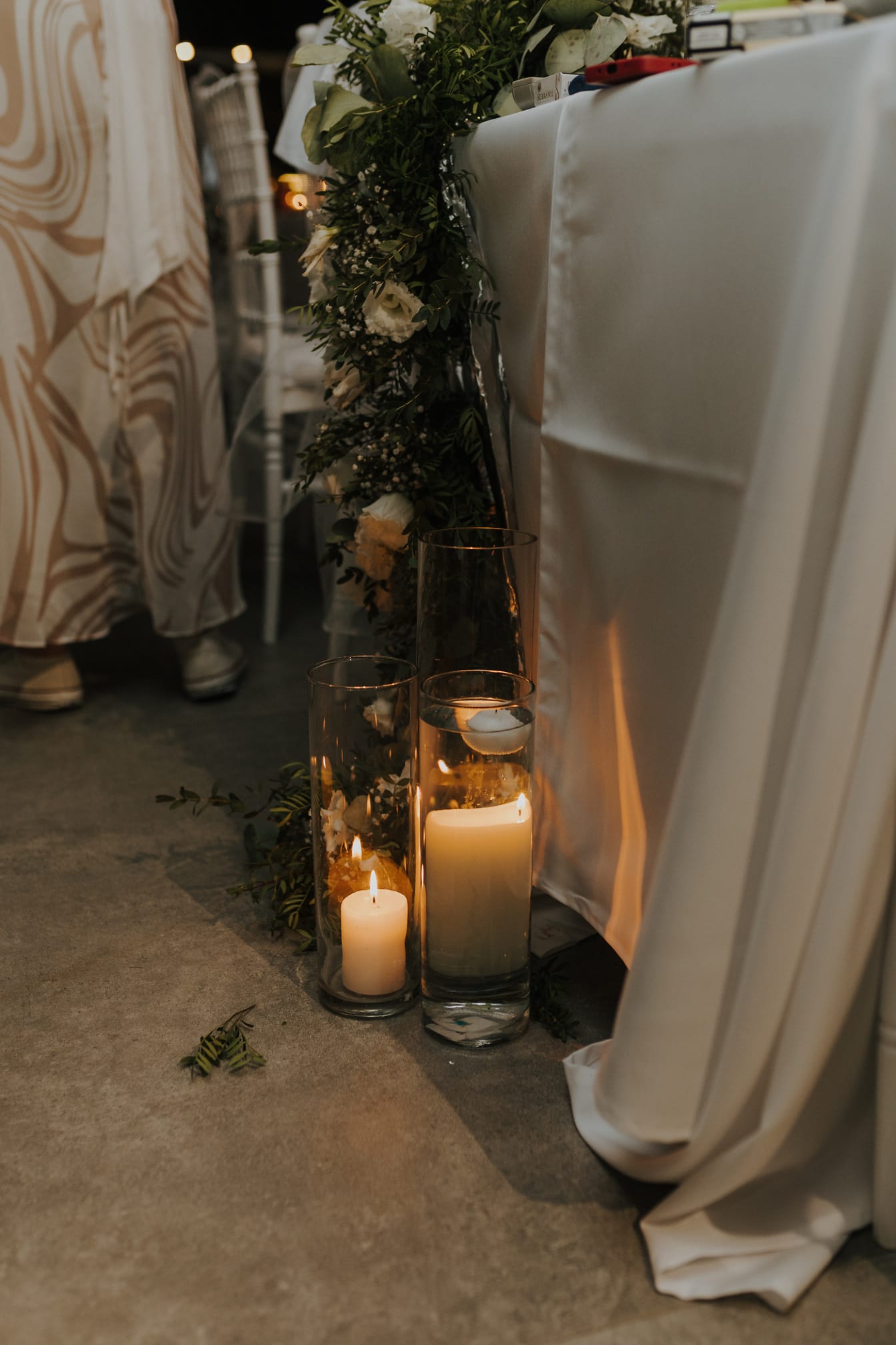 Tyylikkäitä valkoisia kynttilöitä lasimaljakoissa hääpaikalla