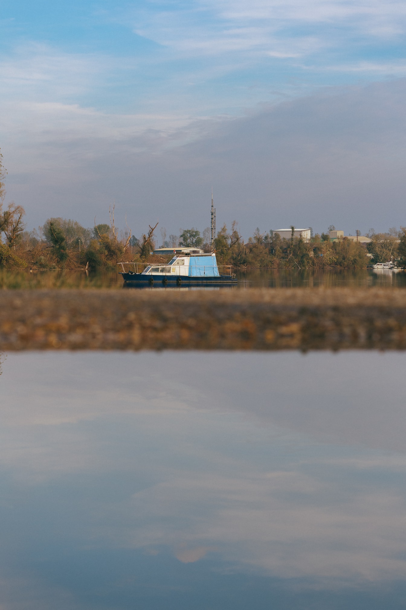 Malá modrá rybárska loď v diaľke na vode jazera