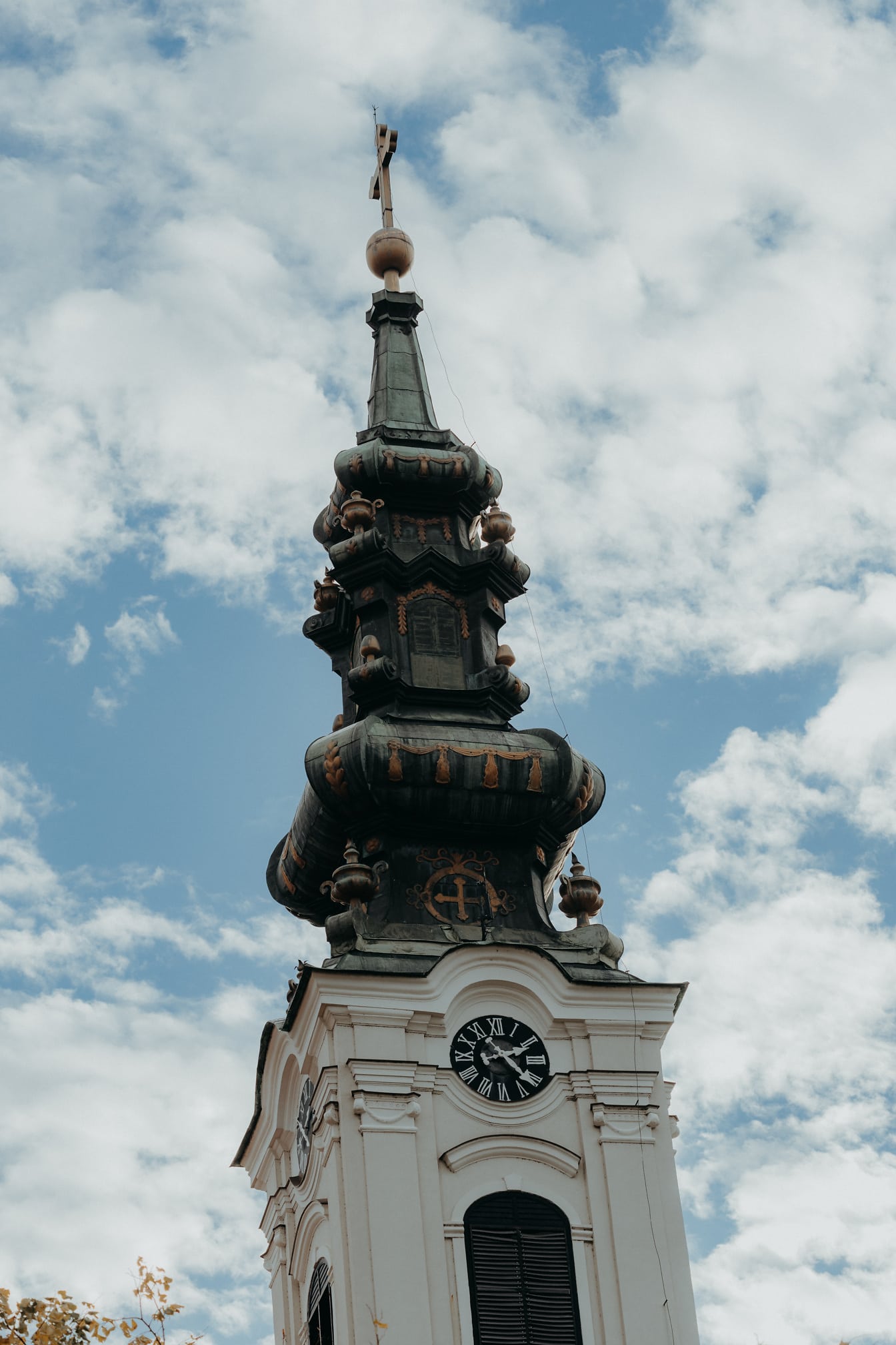 Tmavě zelená kostelní věž pravoslavného kostela se zlatým lesklým křížem