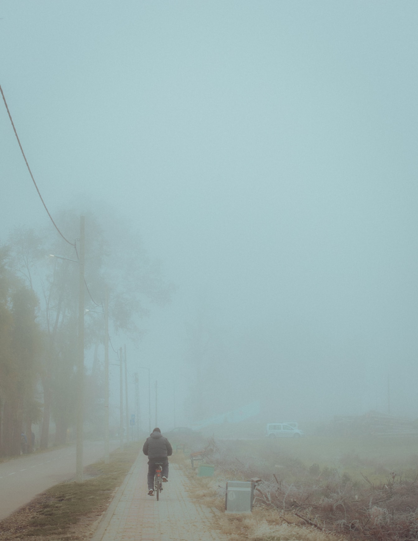 Ciclista che va in bicicletta sul marciapiede nella nebbia