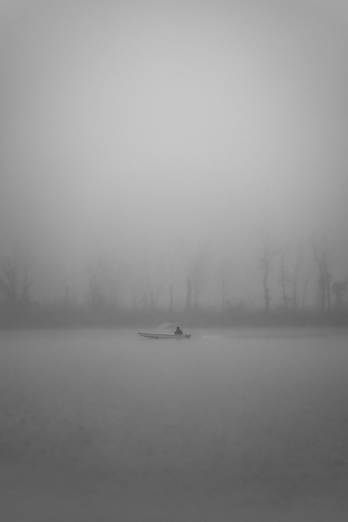 Small fishing boat on foggy Danube river in distance
