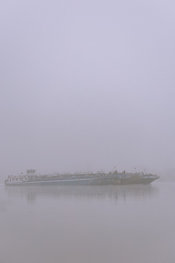 Силует на шлеп товарен кораб в мъгла по река