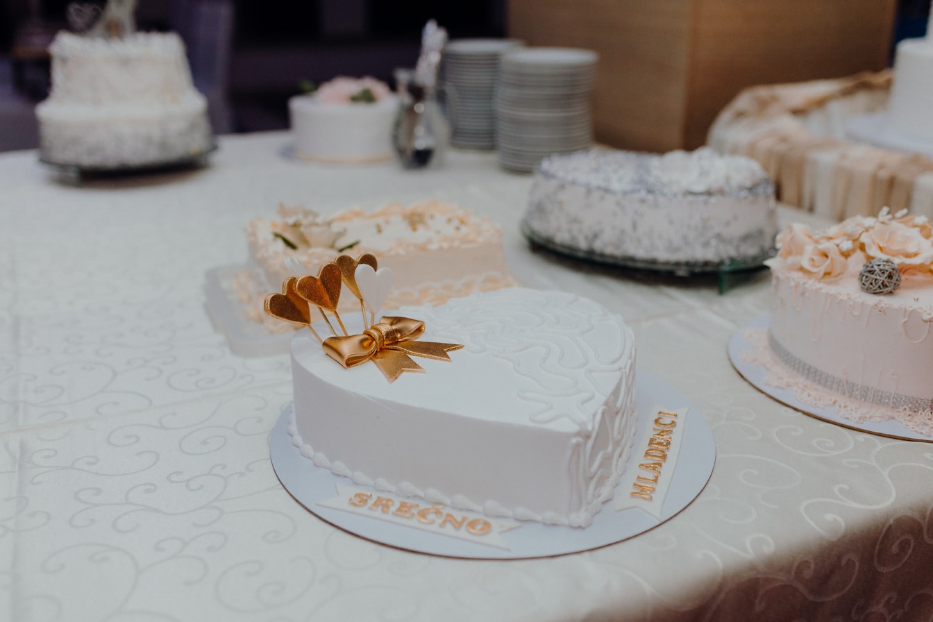 Pastel de bodas cremoso blanco con decoración de espigas de brillo dorado