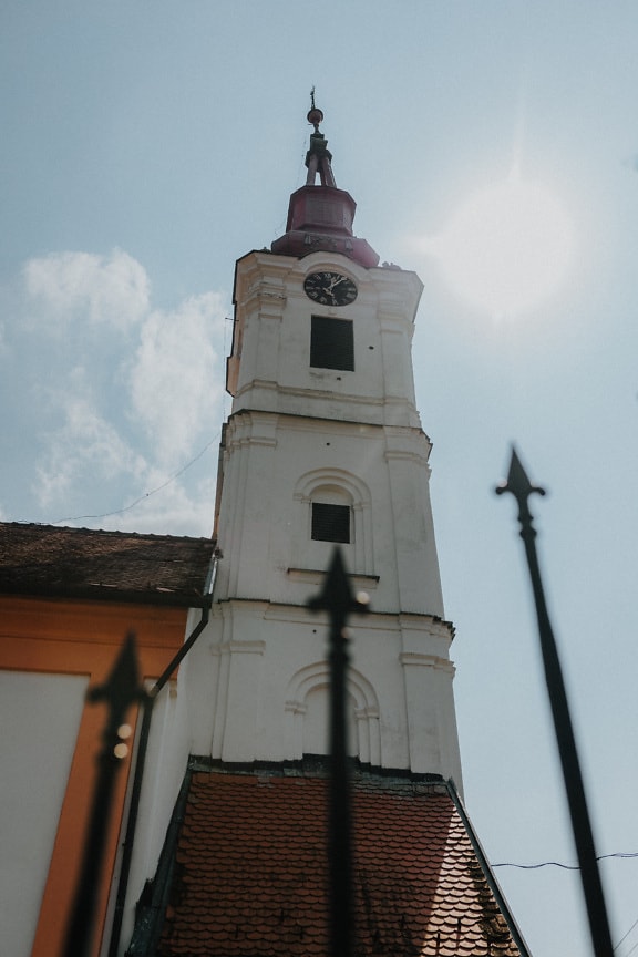 Turnul alb al bisericii ortodoxe cu lumina soarelui în fundal