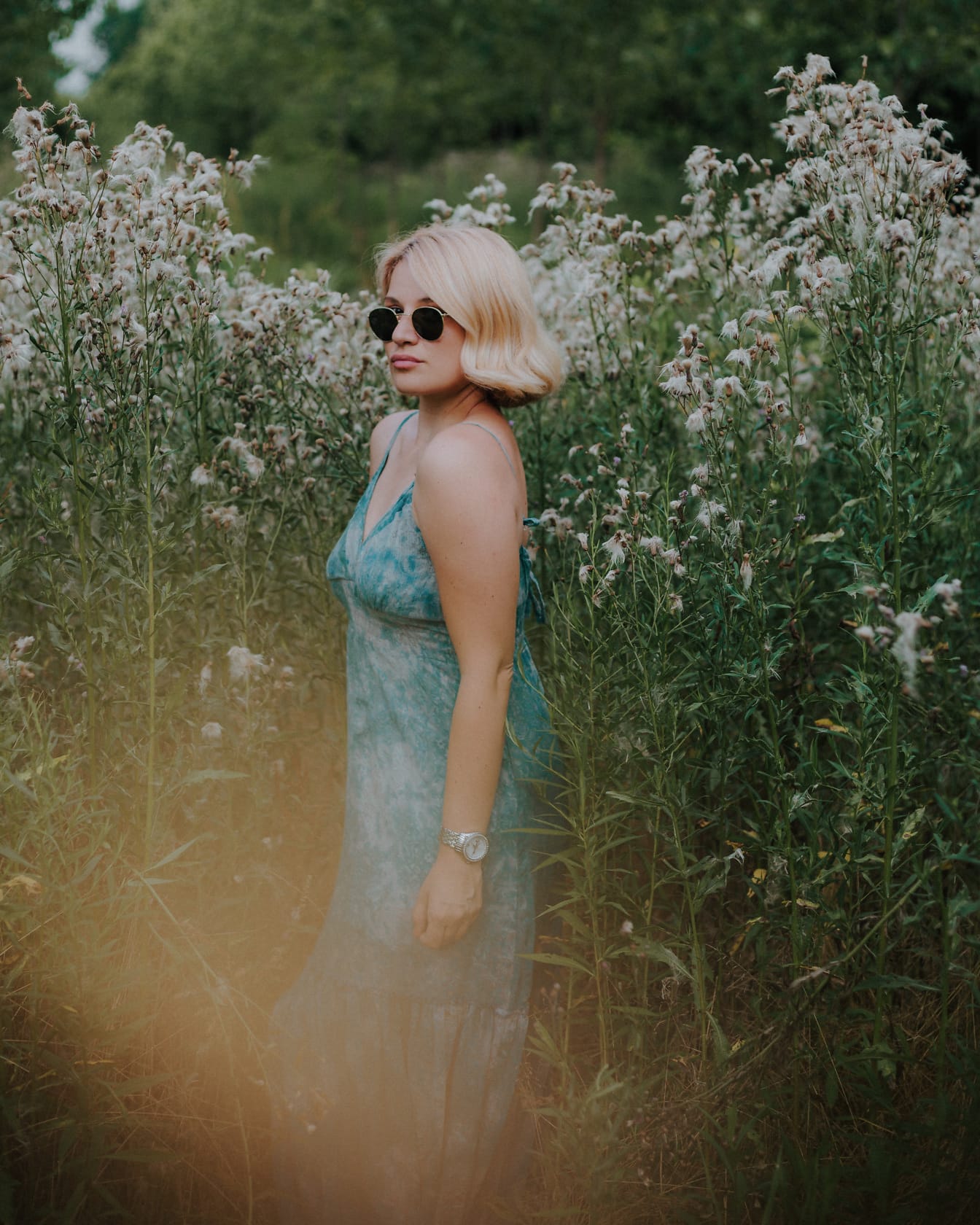 Blondă superbă în rochie verde pastel în iarbă înaltă