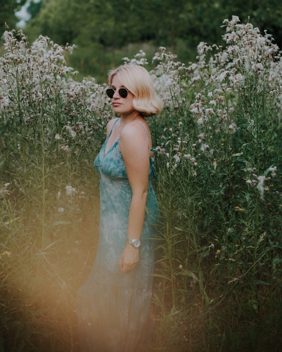 Magnifique blonde en robe vert pastel dans les hautes herbes