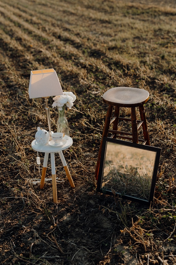 Oglindă elegantă și scaun din lemn cu lampă și ceainic în aer liber