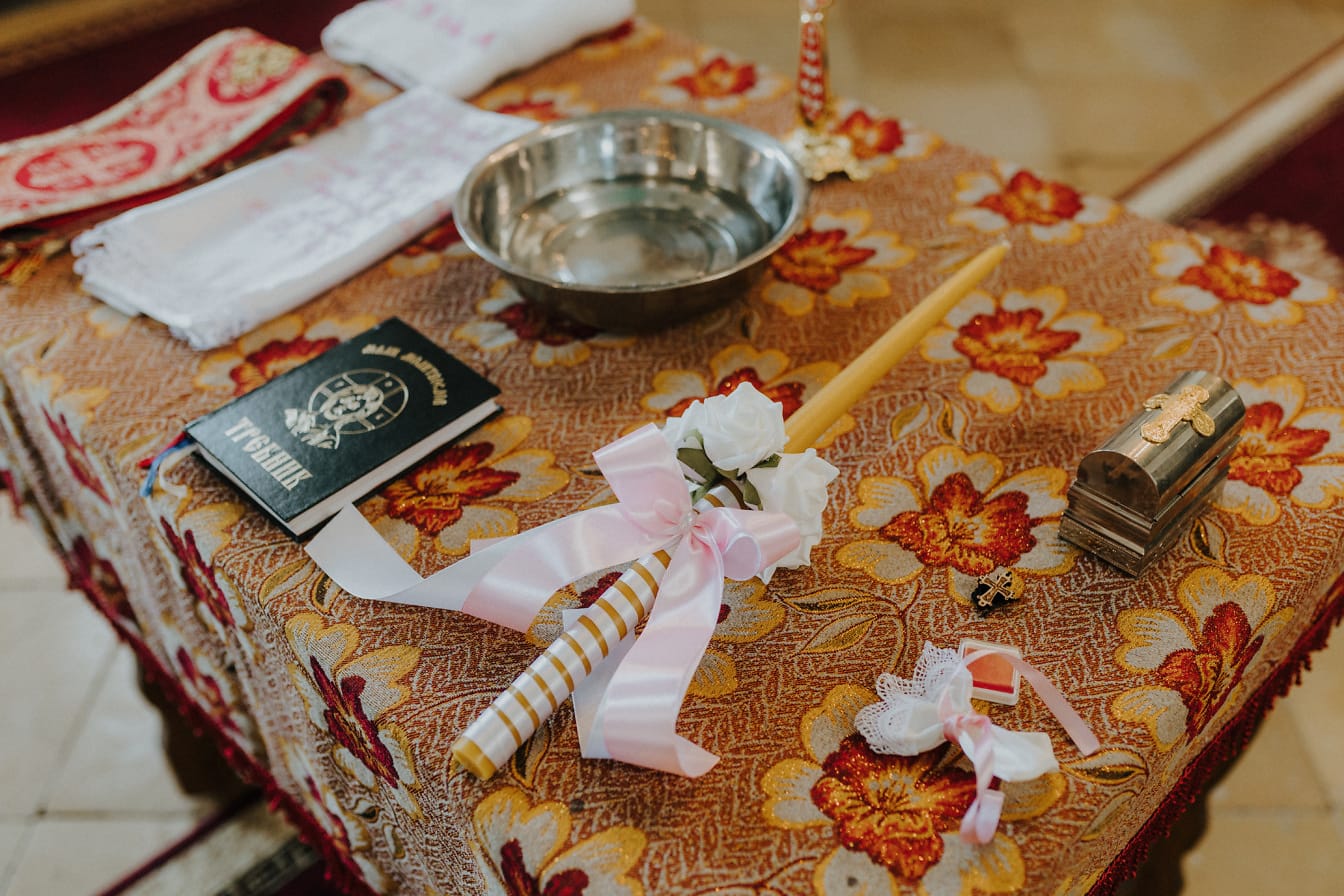 Pöytä, jossa ortodoksinen uskonnollinen kirja ja kynttilä hääseremonian koristelu