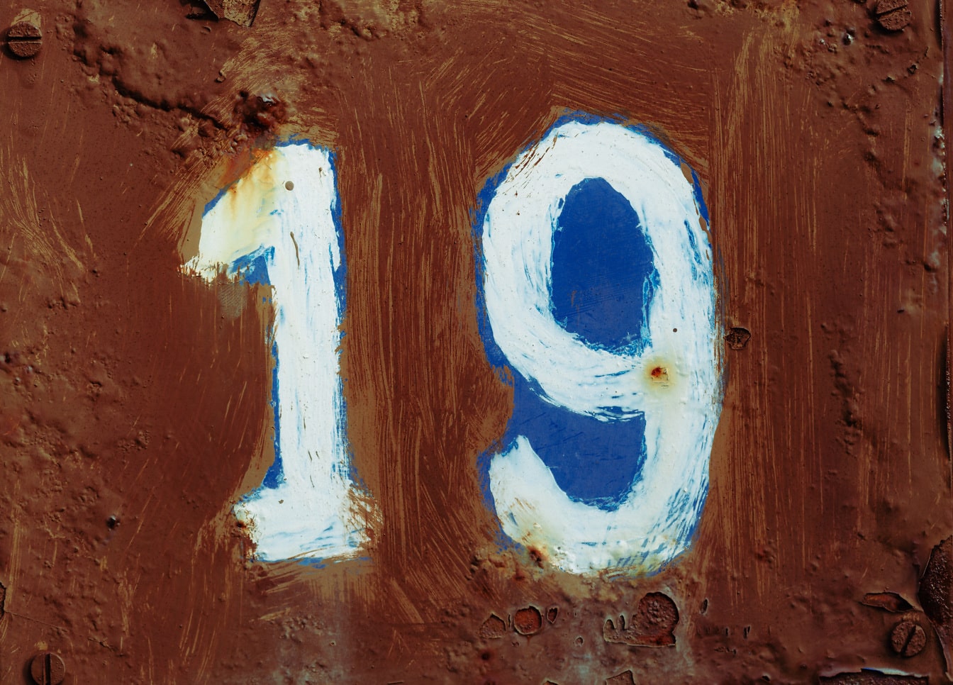 Numero 19 blu scuro su vernice marrone su metallo ruvido arrugginito