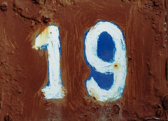 Número 19 azul oscuro sobre pintura marrón sobre metal rugoso oxidado