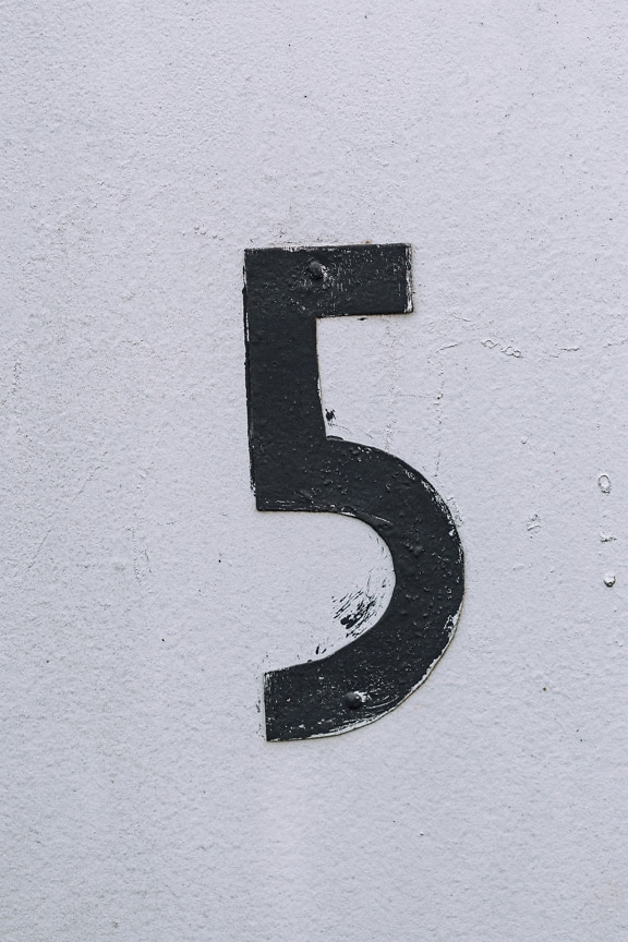 白い壁のクローズアップテクスチャの金属番号5に黒のペイント