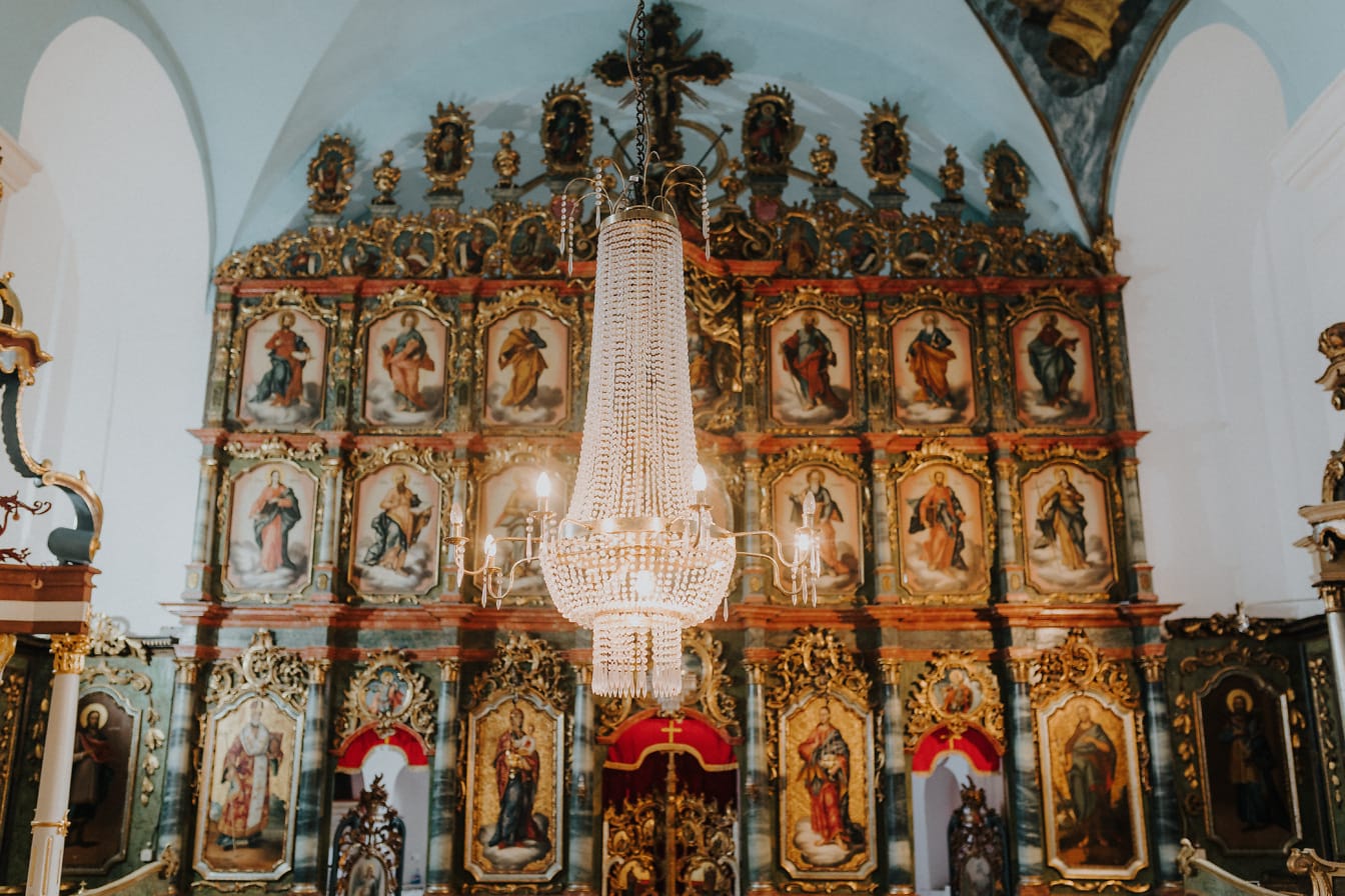 Κρυστάλλινος πολυέλαιος σε ορθόδοξη εκκλησία με φόντο βυζαντινό βωμό