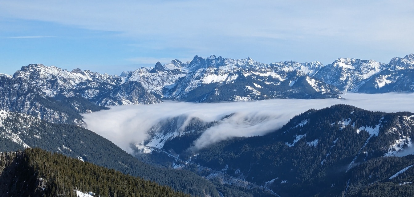 山谷中雾云缭绕的全景，背景是冰冻的山峰