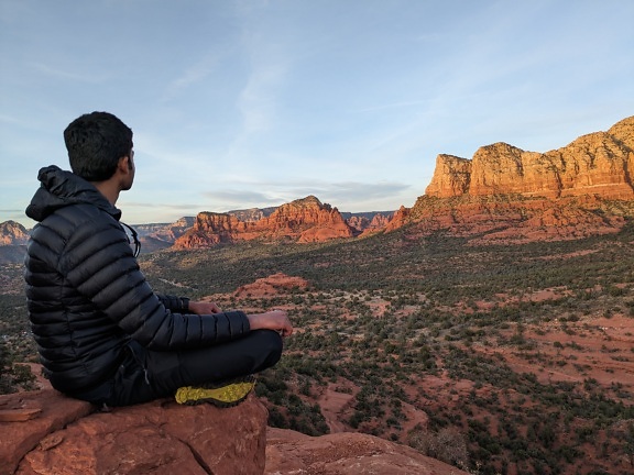 Mutiger Bergsteiger sitzt auf einer hohen Klippe über dem Tal des Grand Canyon