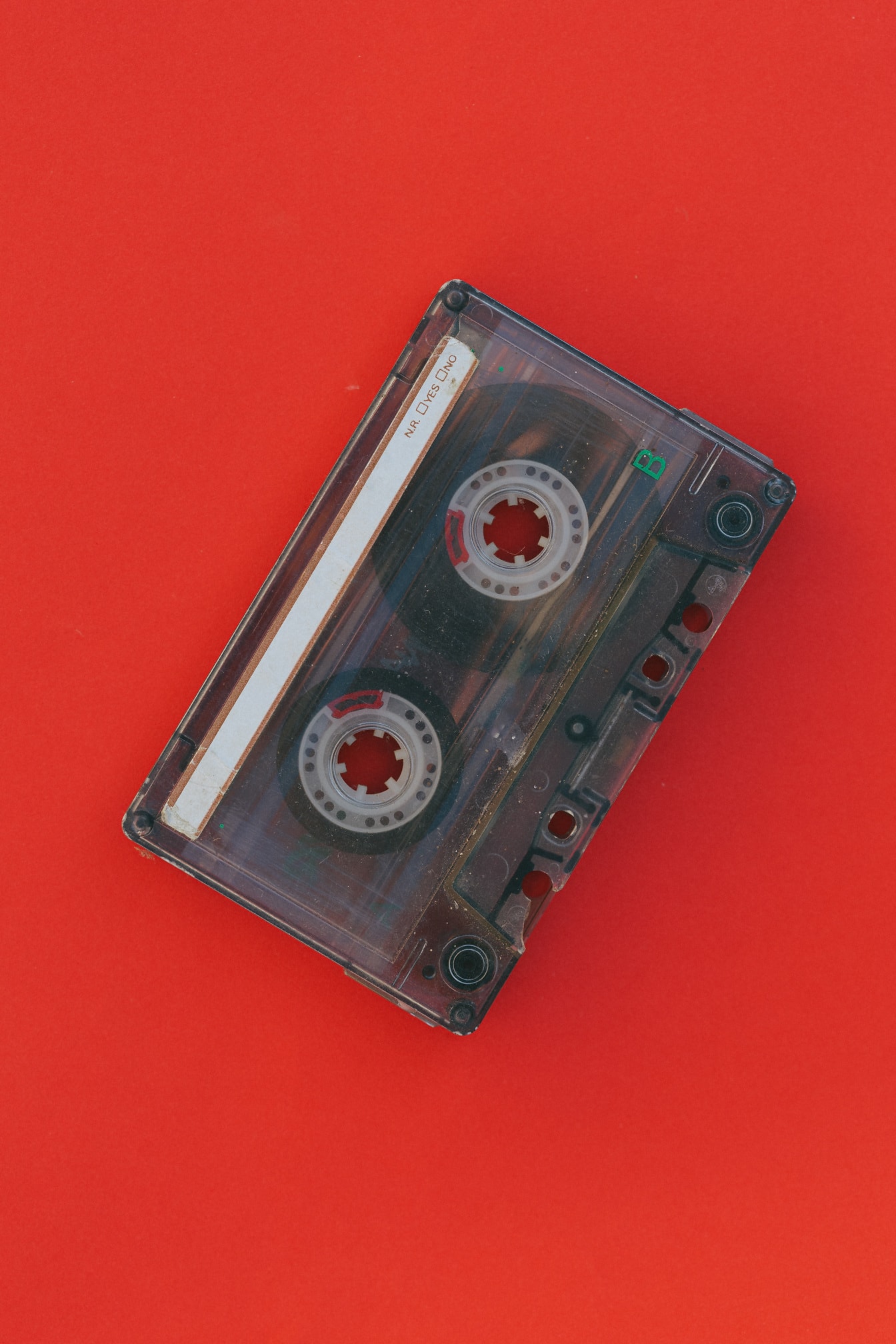 えんじ色の背景に古いプラスチック製のオーディオカセットテープ