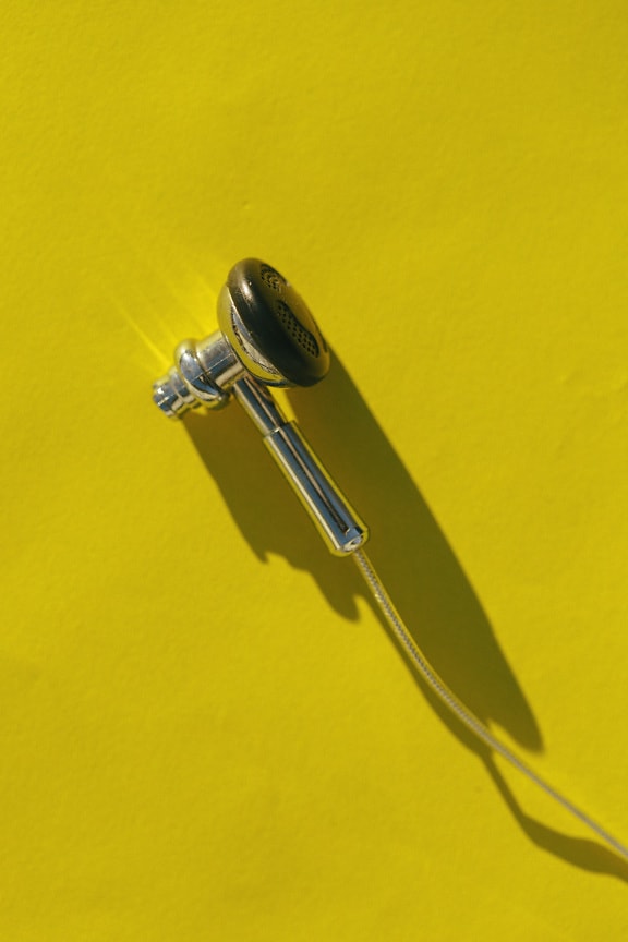 Fones de ouvido pequenos de aço inoxidável close-up no fundo amarelo