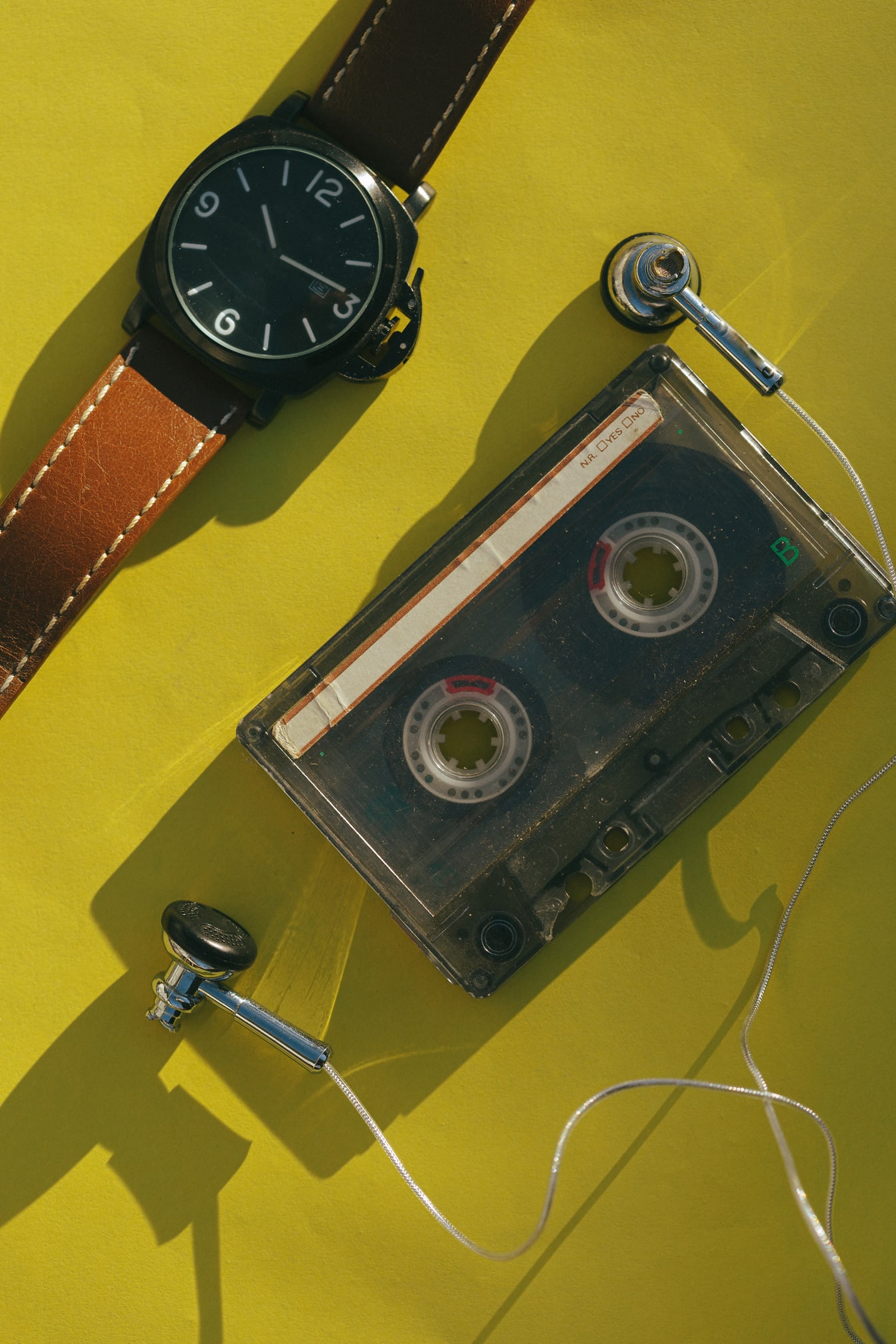 Kaset audio lama dengan headphone dan foto close-up jam tangan