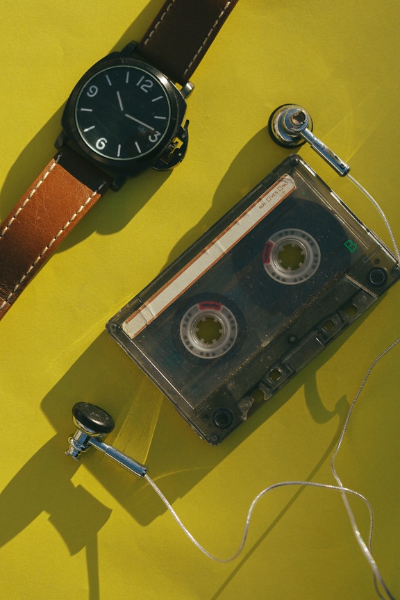 Old audio cassette with headphones and wristwatch close-up photograph