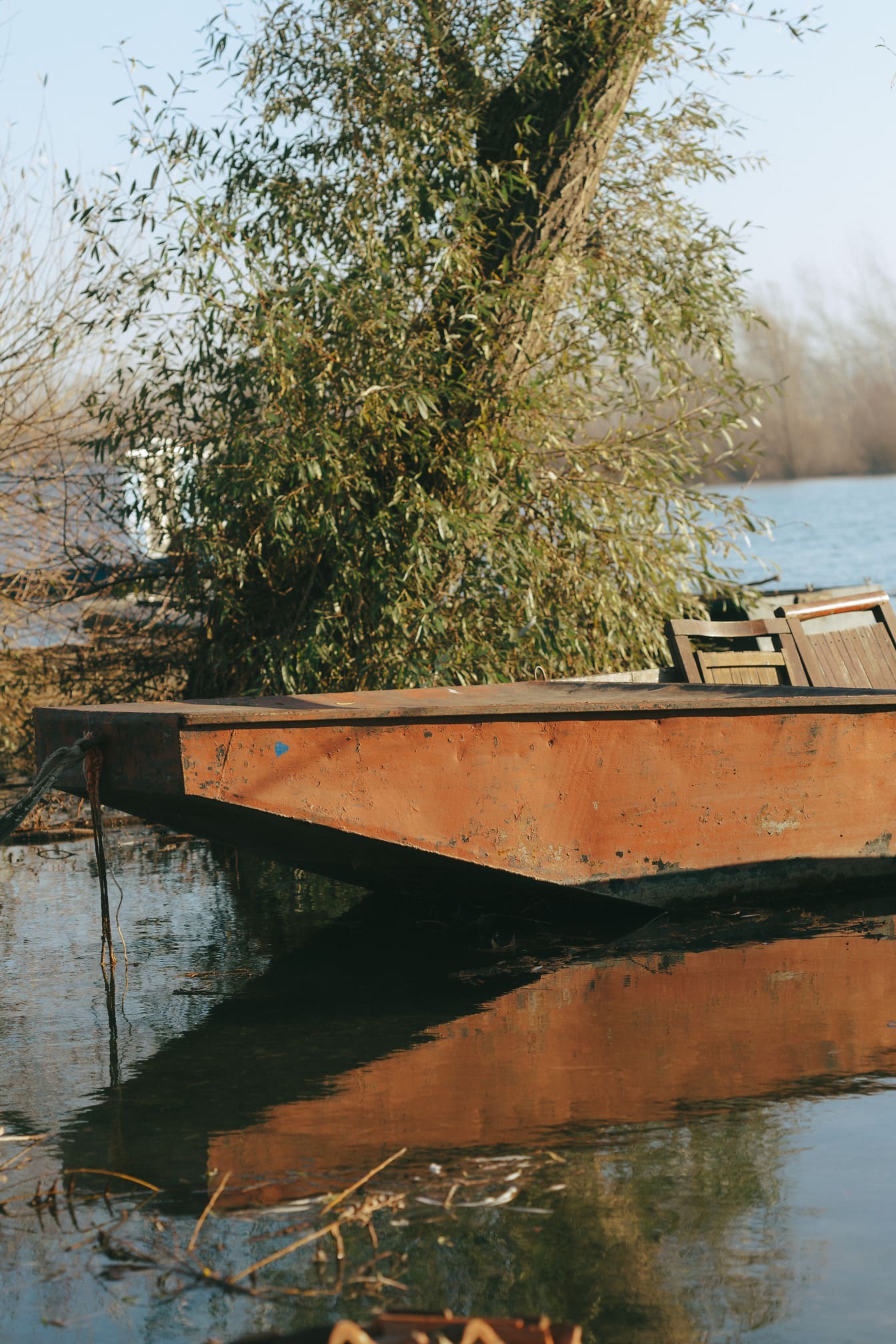 Rezavá železná rybářská loď na břehu řeky detailní fotografie
