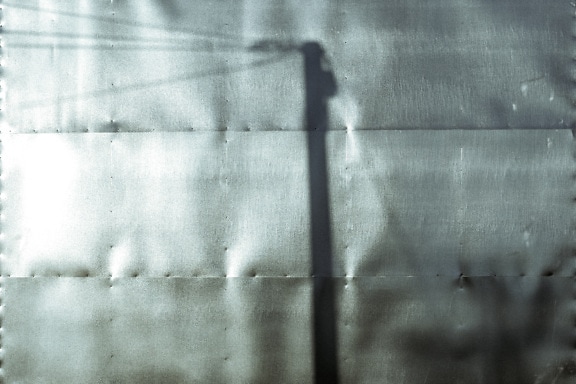 Sjena sjene telefonskog stupa na jednobojnoj fotografiji metalne površine