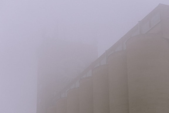 Silhouette of concrete silo building in fog