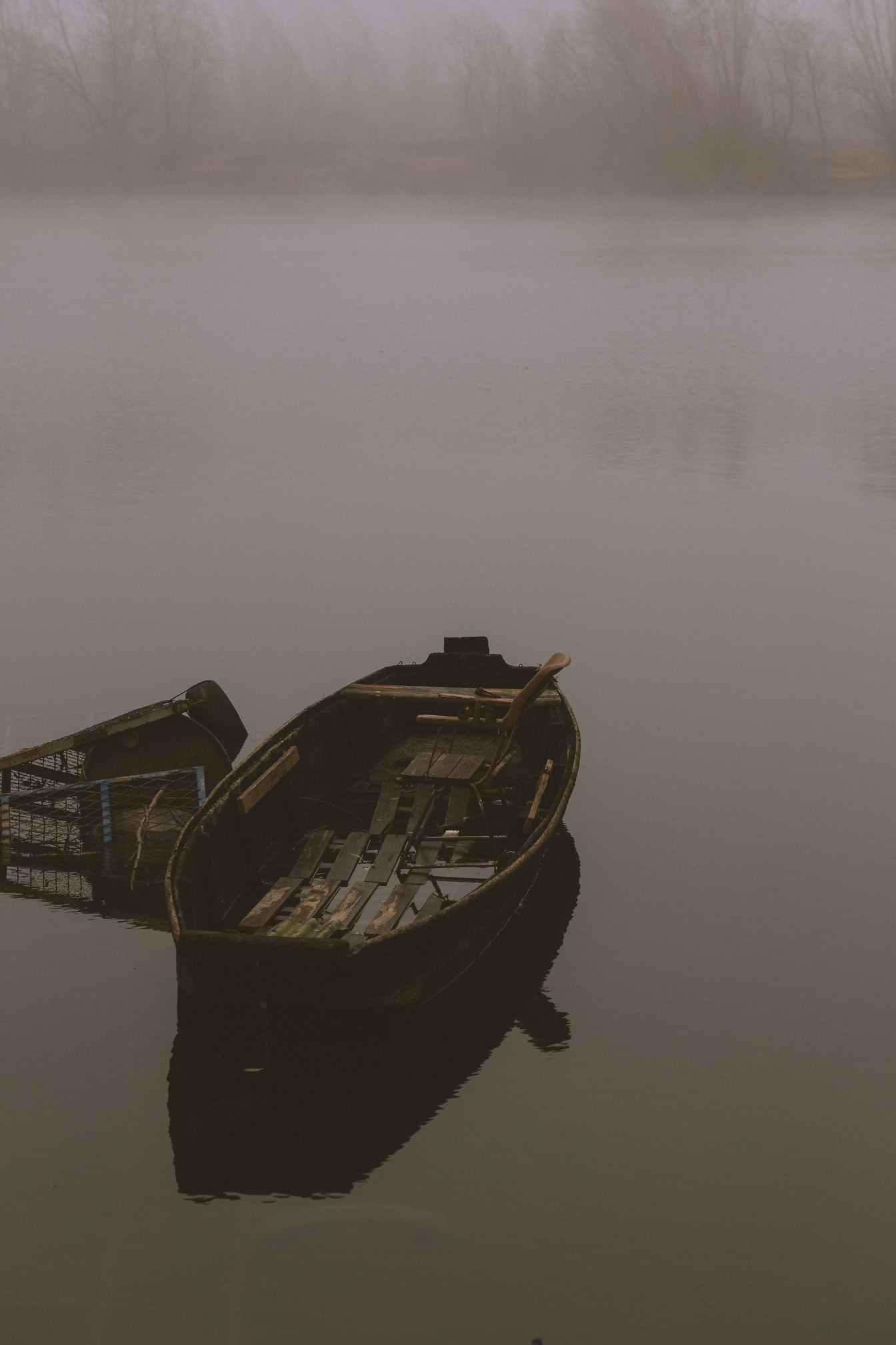 Opuštěné dřevěné rybářské lodě na mlžném břehu řeky