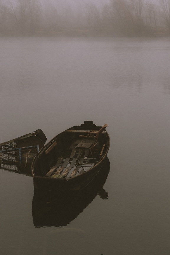 Abandoned wooden fishing boats on foggy riverbank