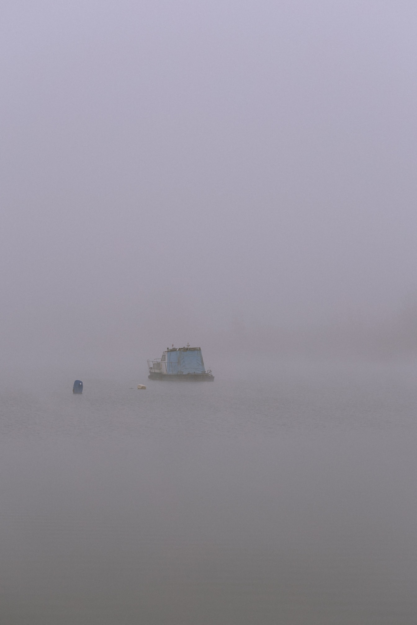 Pequeño barco de pesca azul en el agua en un día de niebla