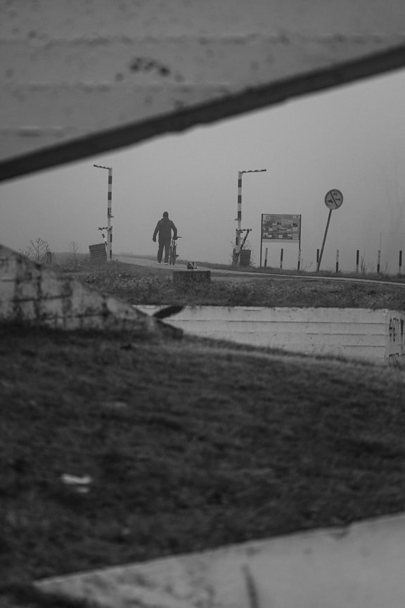 Monochrome photo of person walking on foggy road in rural area