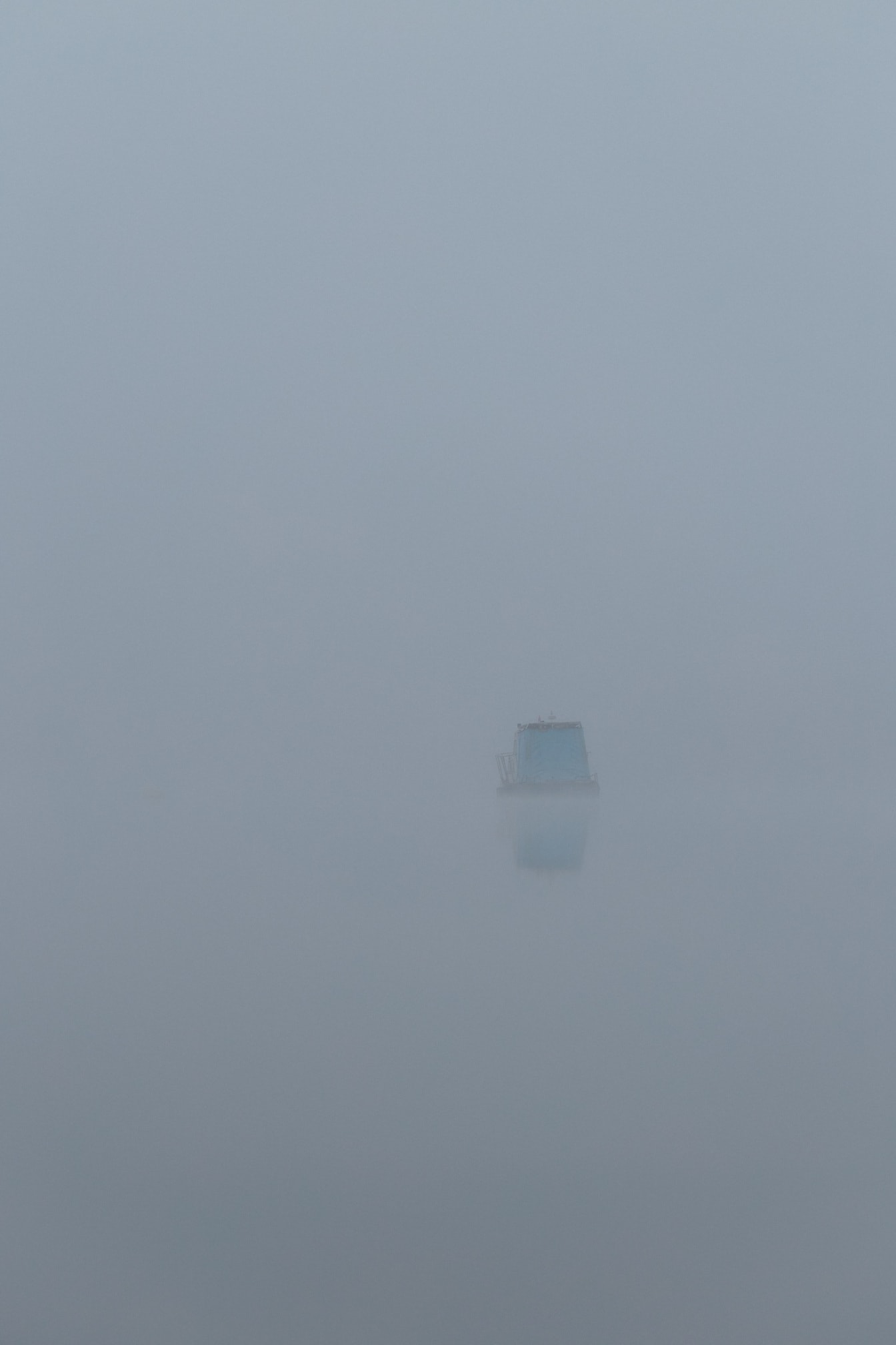 멀리 낚시 보트가 있는 호숫가의 짙은 안개