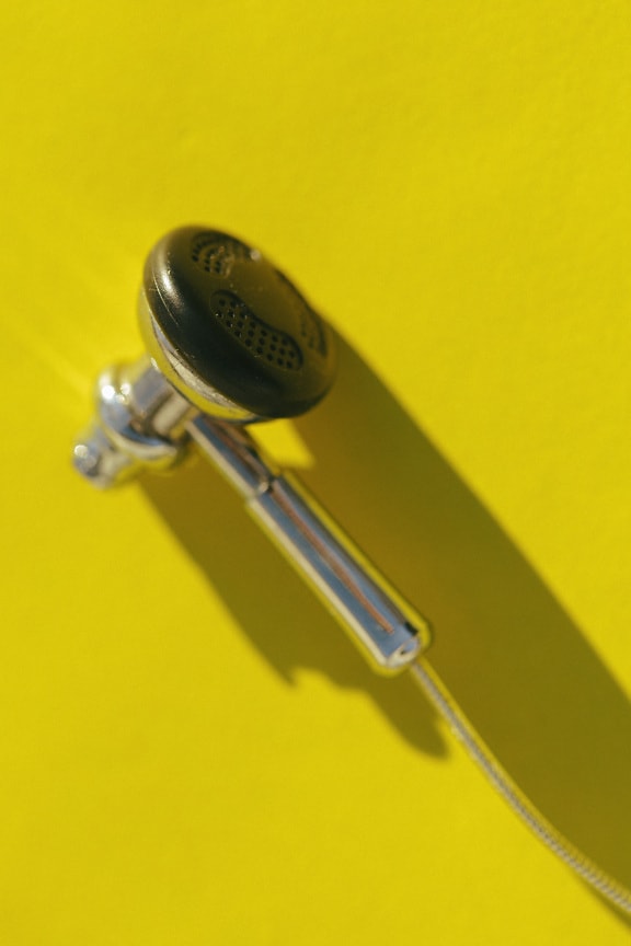 Close-up photo of shining miniature headphone on yellow background