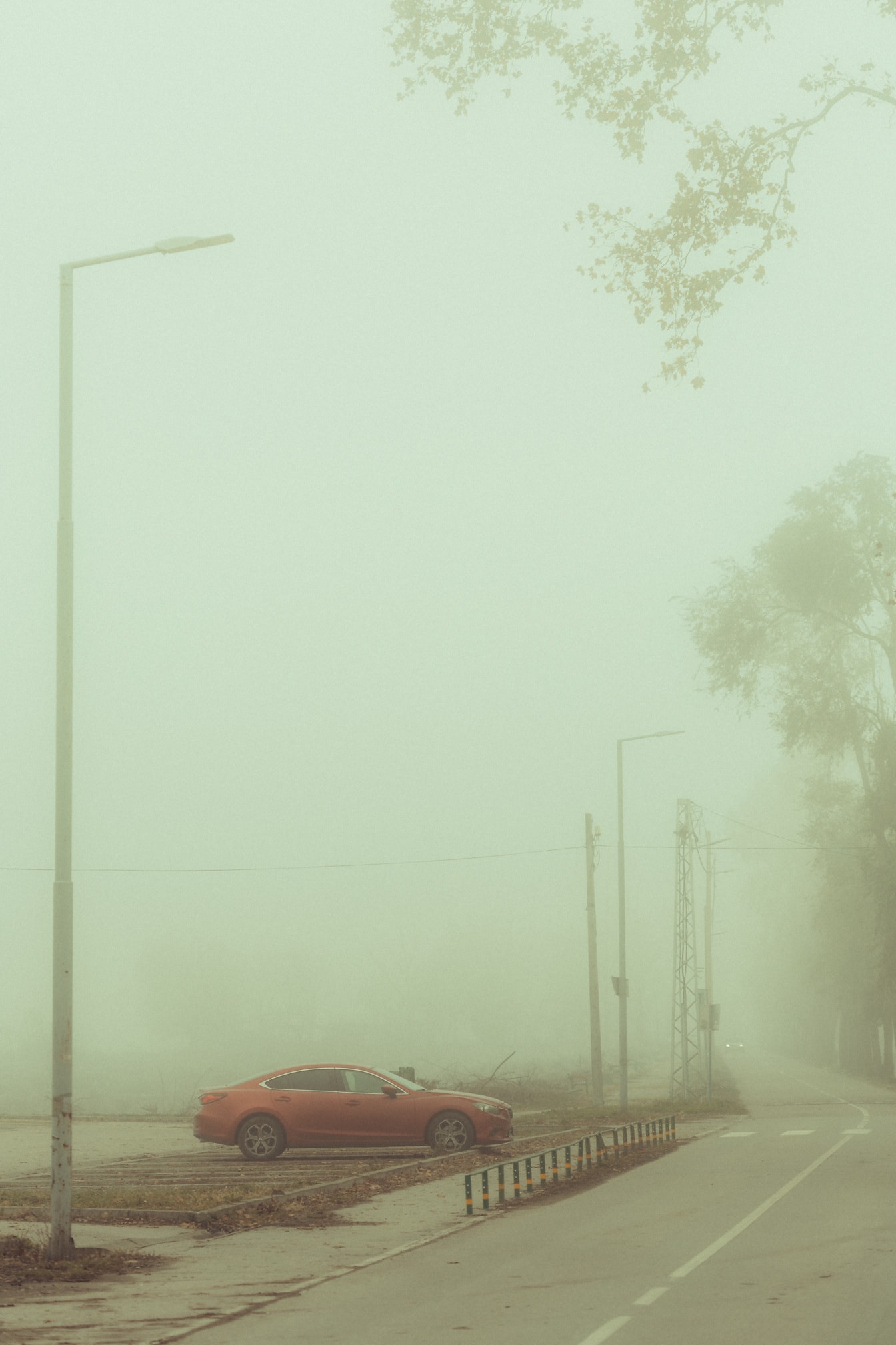Chiếc xe thể thao sedan màu đỏ sẫm trên bãi đậu xe sương mù