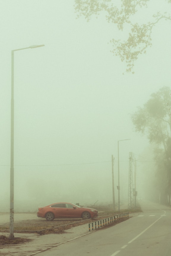 Тъмночервен седан спортна кола на мъглив паркинг