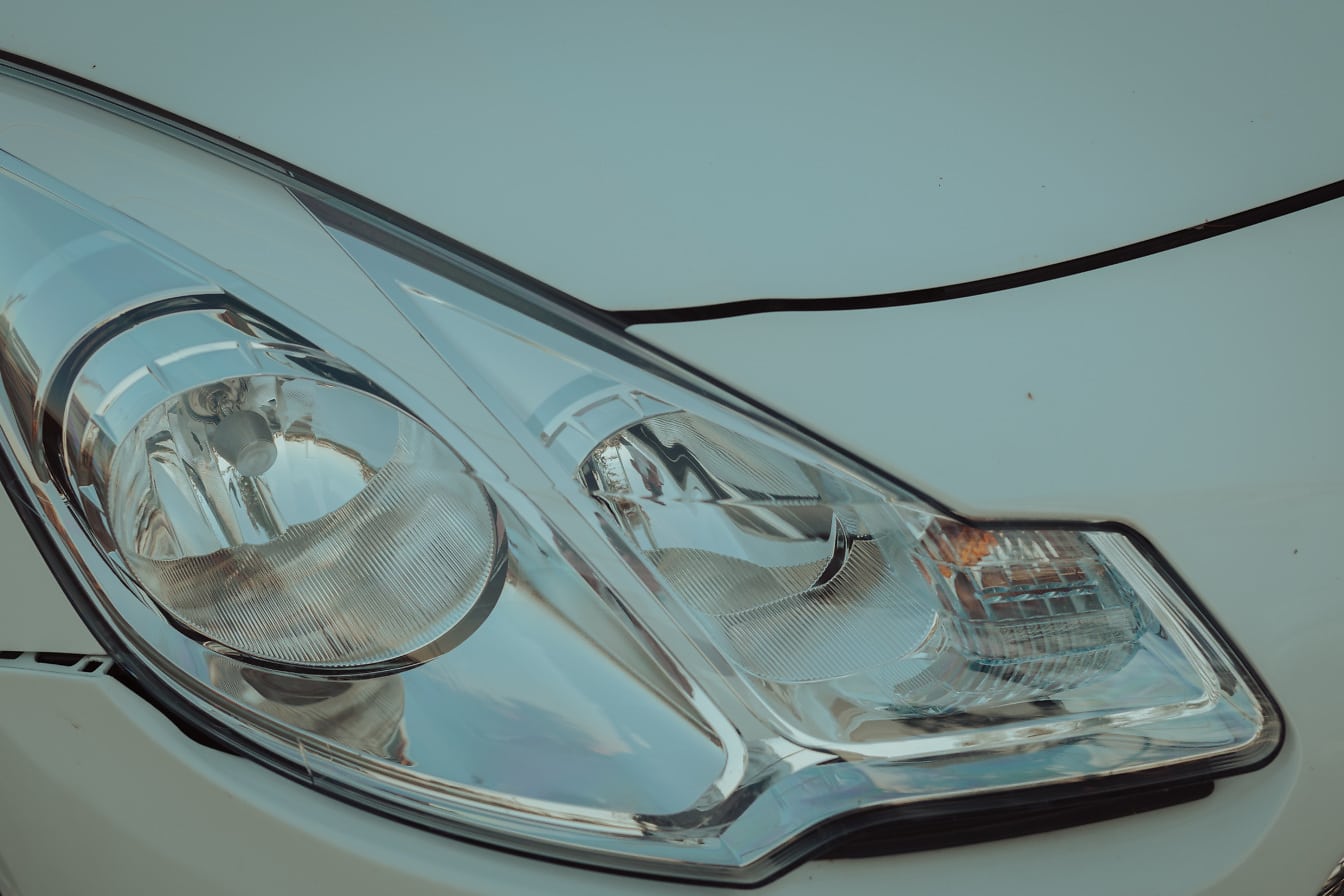 Close-up of headlight of metallic white sedan car