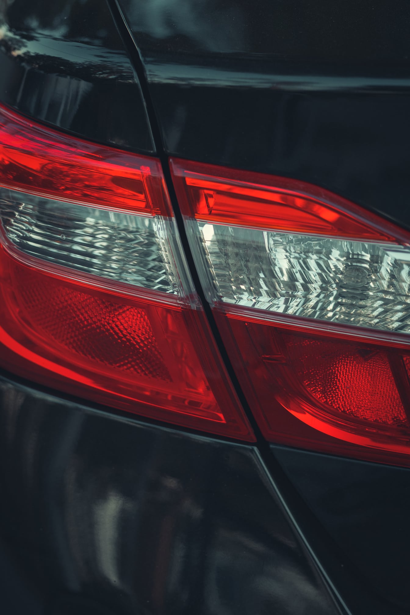 Luz traseira de plástico vermelho escuro no close-up do carro sedan metálico preto