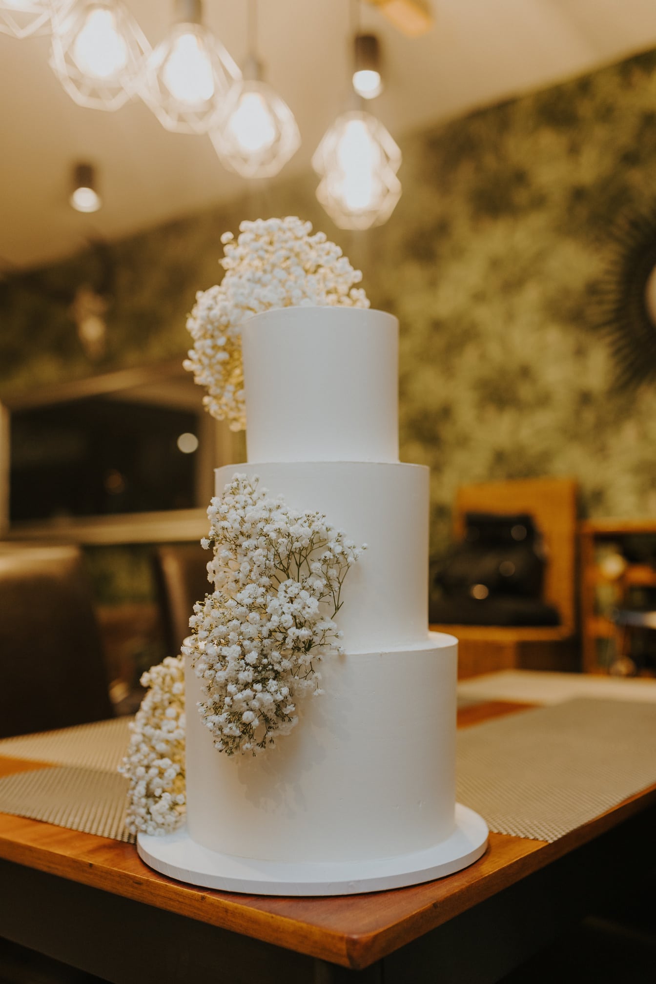 Elegant hvid bryllupskage med hvid blomsterdekoration på restaurantbord