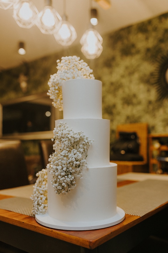 Élégant gâteau de mariage blanc avec décoration de fleurs blanches sur la table du restaurant