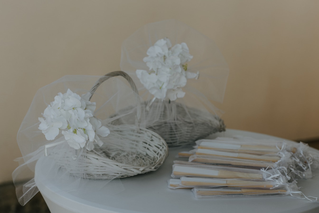 Elegantes cestas de mimbre blanco hechas a mano y abanicos de mano sobre la mesa