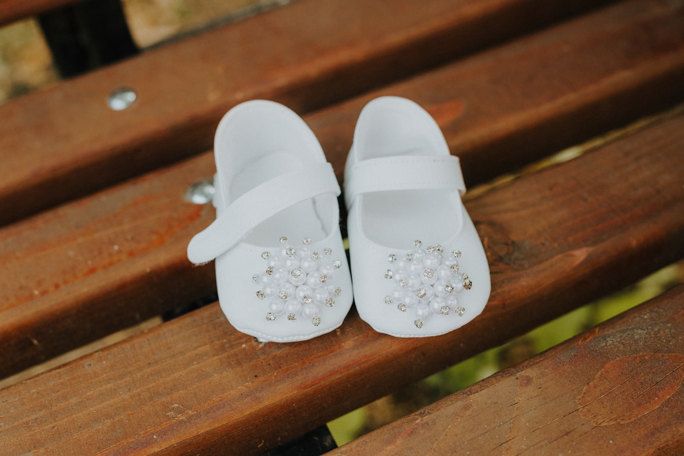 Adorable elegant white baby shoes with pearls close-up photograph