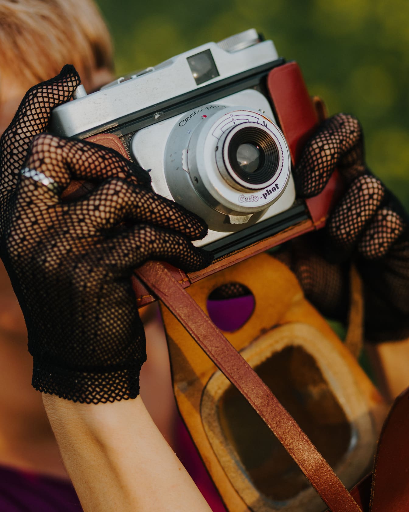 Mujer con guantes de glamour sosteniendo una cámara de fotos pasada de moda