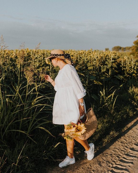 Countryside cowgirl in white dress in agricultural field