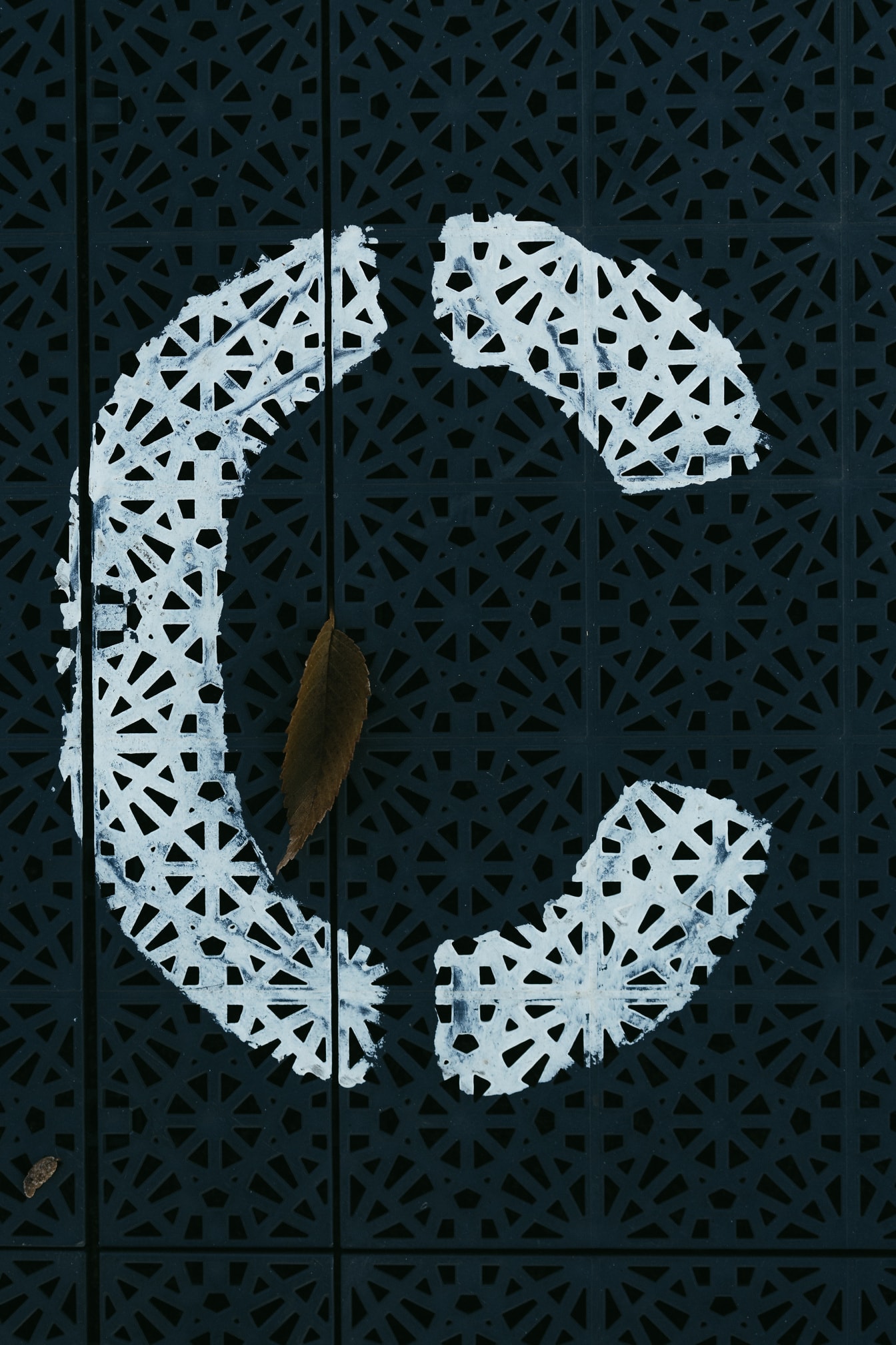 Wit teken (C) op donker plastic met geometrisch patroon