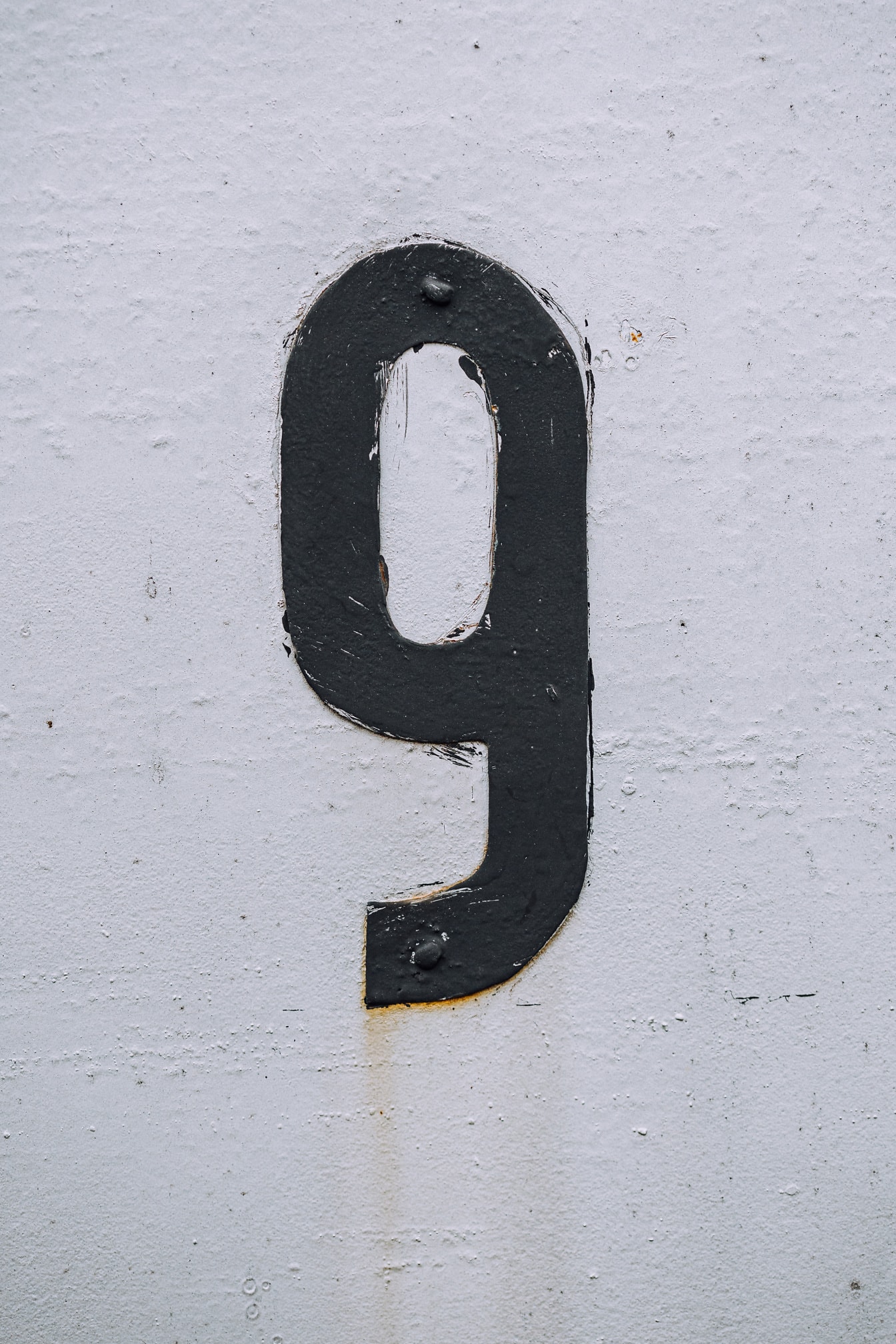 Металлический номер девять (9) черной краской на белом фоне