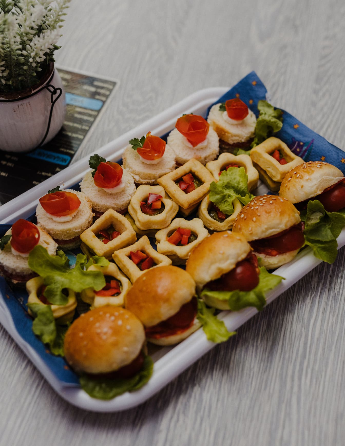 Plastbricka med läckra minismörgåsar och hamburgare med salladsgarnering