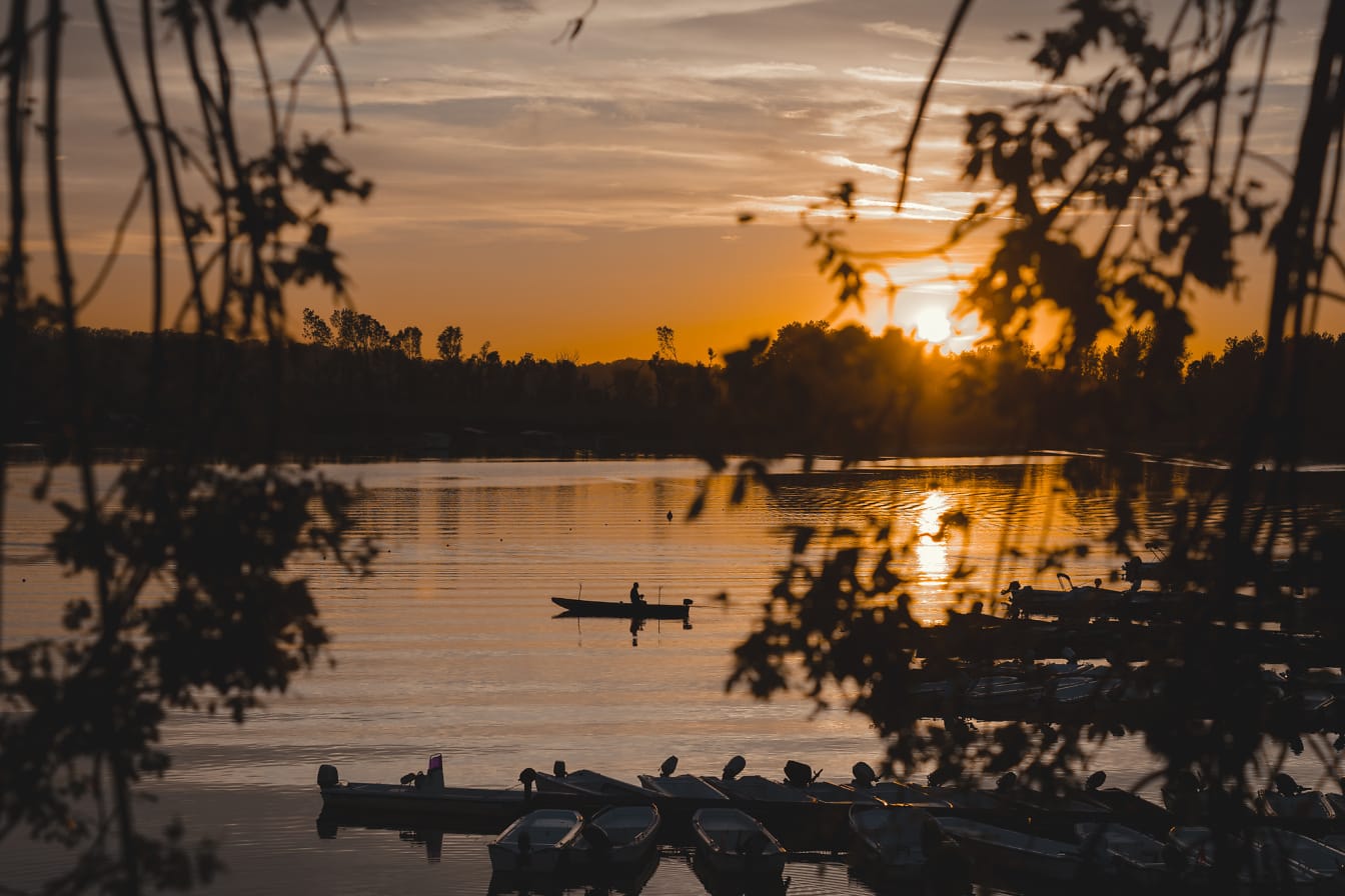 Kalastajan siluetti kalastusveneessä Tikvara-järvellä auringonlaskun aikaan