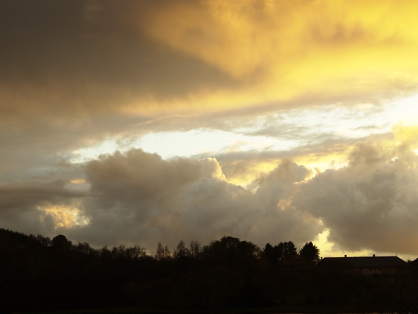 Auringonlasku ja kellertävänruskeita pilviä taivaalla