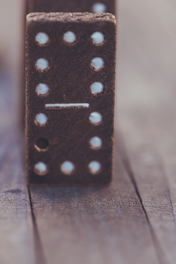 Old brown wooden domino standing vertical close-up