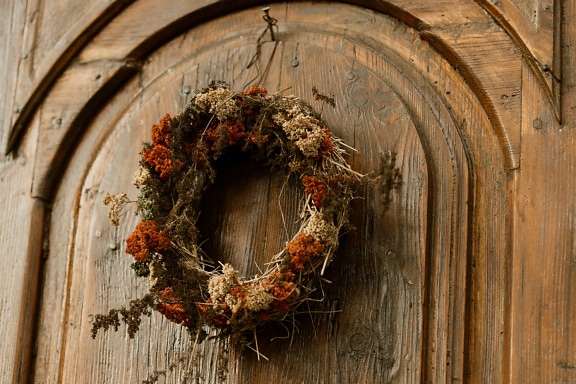 手作りの彫刻が施された玄関ドアに吊るされた花輪