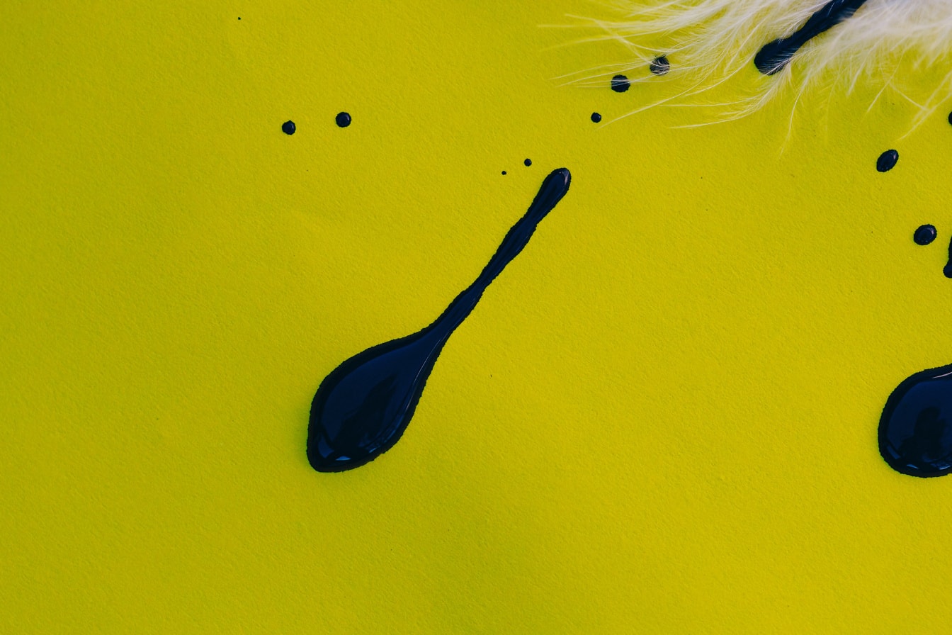 Stänk av svart akvarellfärg på en gul yta